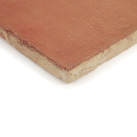Die Terrakottafliese liegt flach und zeigt ihre raue, rotbraune Oberfläche und die beige Unterseite, isoliert auf einem schlicht