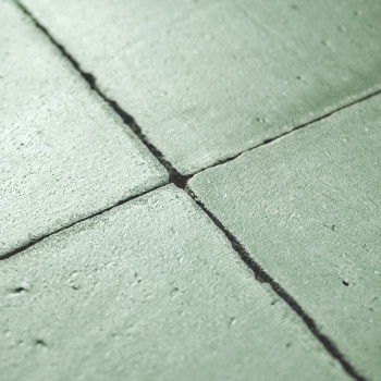 Azulejos de terracota verde alineadas en un patrón de cuadrícula, mostrando pequeñas costuras entre ellas, posiblemente instalad