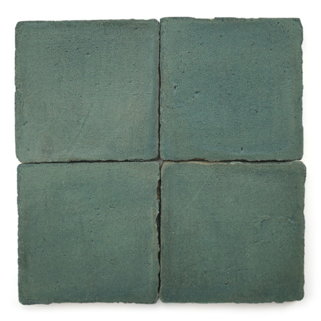 Cuatro Azulejos cuadradas de terracota de color azul verdoso están dispuestas en una cuadrícula de dos por dos, mostrando una su