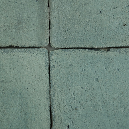 Cuatro Azulejos de terracota verdosas forman un patrón de cuadrícula. cada mosaico muestra una superficie texturizada y rugosa e