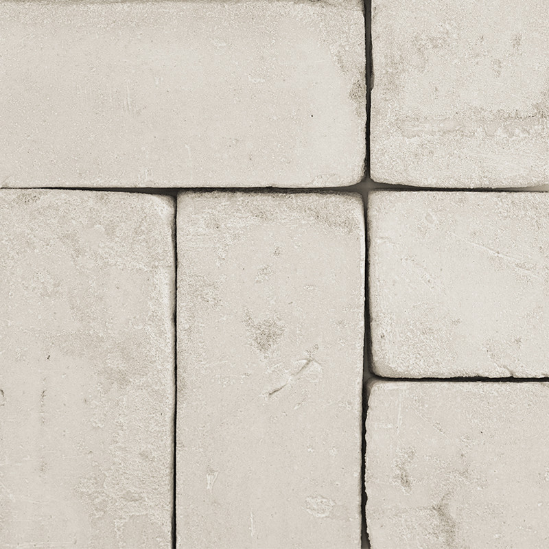Les carreaux rectangulaires en terre cuite reposent à plat, formant un motif imbriqué. Autour d’eux, un coulis lisse aux tons ne