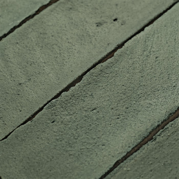Los azulejos de terracota verde están alineadas con líneas de lechada visibles, creando una textura rústica en la superficie de 