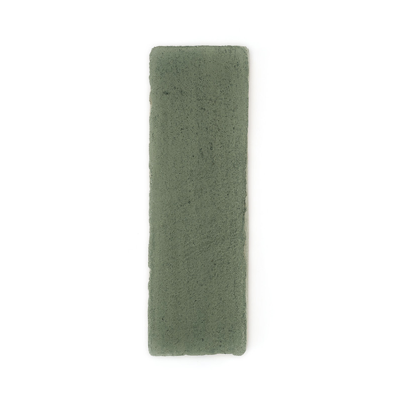 Una baldosa rectangular de terracota verde se encuentra plana sobre un fondo blanco liso, mostrando su textura rugosa.