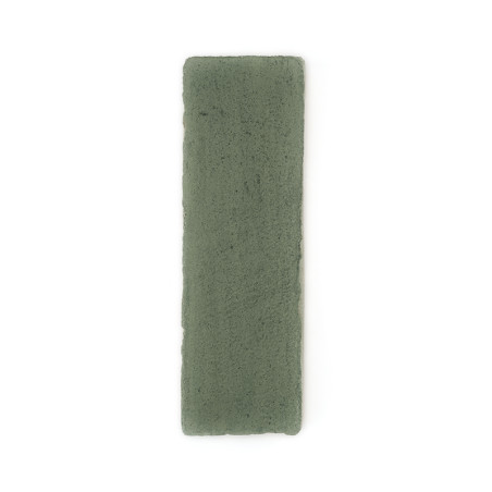 Una baldosa rectangular de terracota verde se encuentra plana sobre un fondo blanco liso, mostrando su textura rugosa.