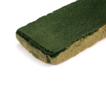 Carreau rectangulaire en terre cuite vernissée verte, reposant sur une surface blanche unie.