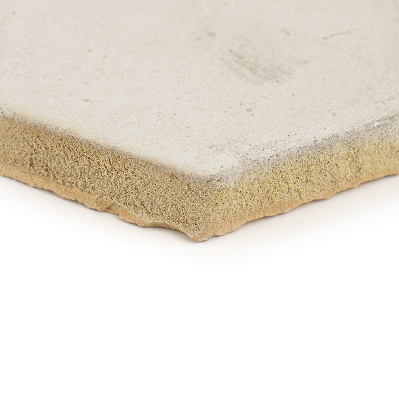 Square terracotta tile sits flat, displaying a rough, textured edge, in a white, minimalistic environment.