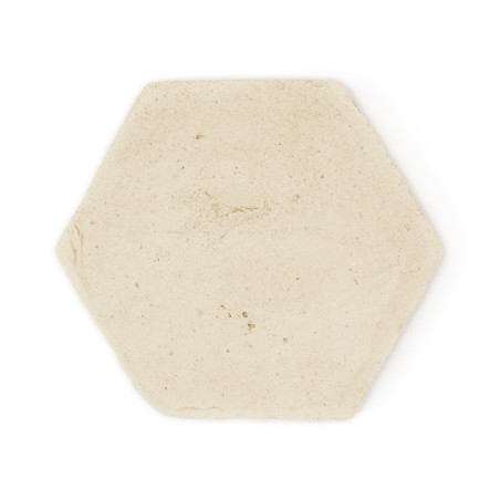 Baldosa de terracota hexagonal sobre un fondo blanco liso, que muestra una superficie suave y de color beige claro con una textu