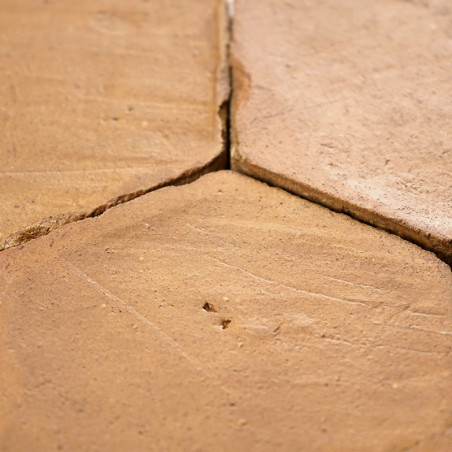 Azulejos hexagonales de terracota yacen puestas a tierra, mostrando un ligero desgaste, formando un patrón de suelo rústico y te