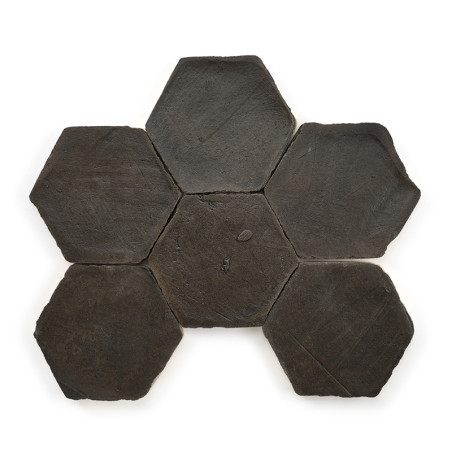 Azulejos de terracota hexagonales dispuestas simétricamente sobre un fondo blanco, formando un patrón similar a una flor.