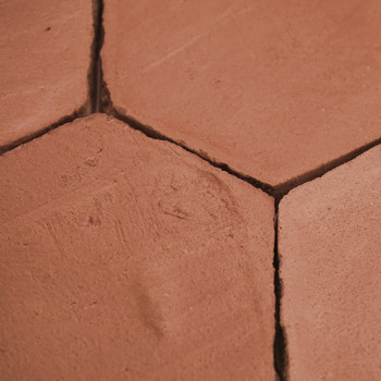 Azulejos de terracota hexagonales se encuentran adyacentes, revelando un desgaste sutil, en un piso muy colocado y con lechada i