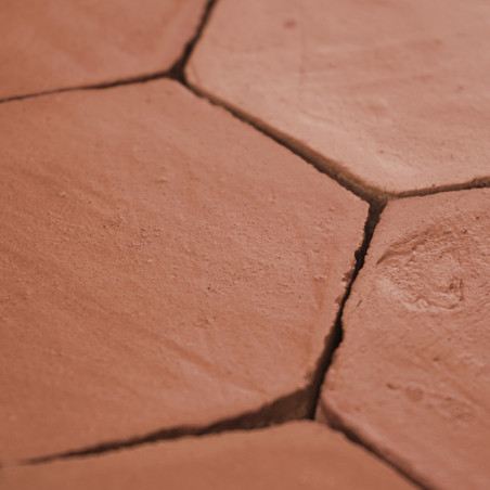 Los azulejos de terracota hexagonales forman un piso rústico, mostrando grietas naturales y tonos tierra en un patrón muy espaci