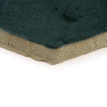 A green-glazed terracotta tile sits against a white background, highlighting its rough, unglazed edge.