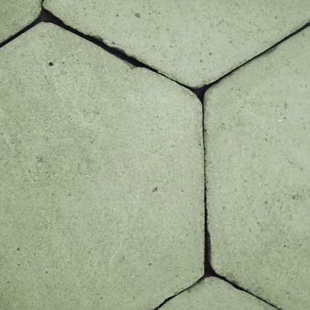 Hexagonal terracotta tiles interlock, forming a seamless pattern on a floor, creating a rustic and textured surface.