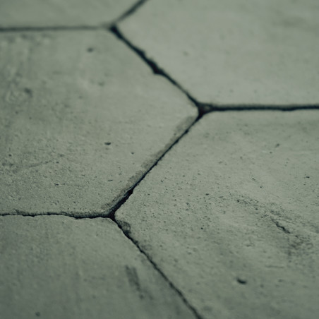 Zeshoekige terracottategels werden met elkaar verbonden, met zichtbare naden, waardoor een gestructureerd, rustiek oppervlak met