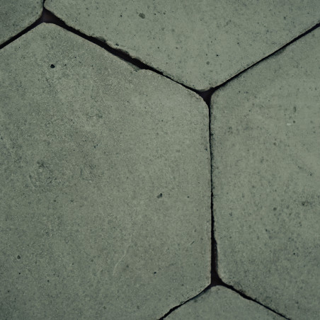 Zeshoekige terracottategels, dicht bij elkaar gelegd, vormen een structuurpatroon op de vloer, waardoor een geometrische, rustie