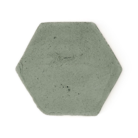 Zeshoekige terracotta tegel die plat ligt en een glad, gedempt groen oppervlak vertoont, afgezet tegen een effen witte achtergro