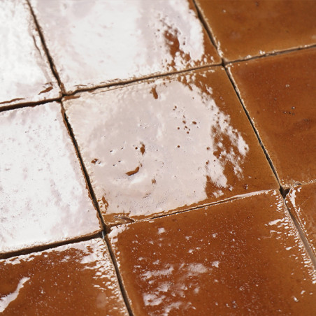 Carreaux en terre cuite brillante réfléchissant la lumière, disposés selon un motif en grille, entourés de carreaux adjacents to
