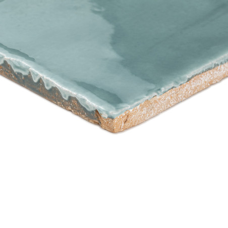Les carreaux en terre cuite présentent un vernis turquoise brillant avec des bords lisses, reposant sur un fond blanc uni pour l