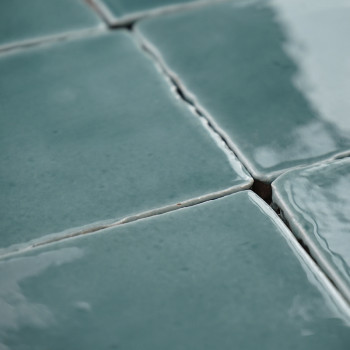 Groene terracottategels zijn dicht op elkaar geplaatste, enigszins oneffen oppervlakken die het licht reflecteren, waardoor een 