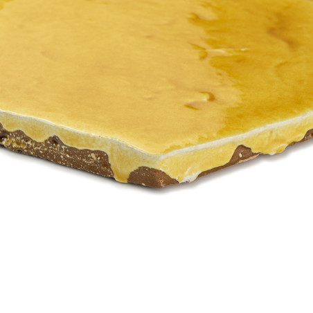 Terracotta tegel met een glanzende, gele glazuur en ruwe randen. rustend op een neutrale, witte achtergrond.