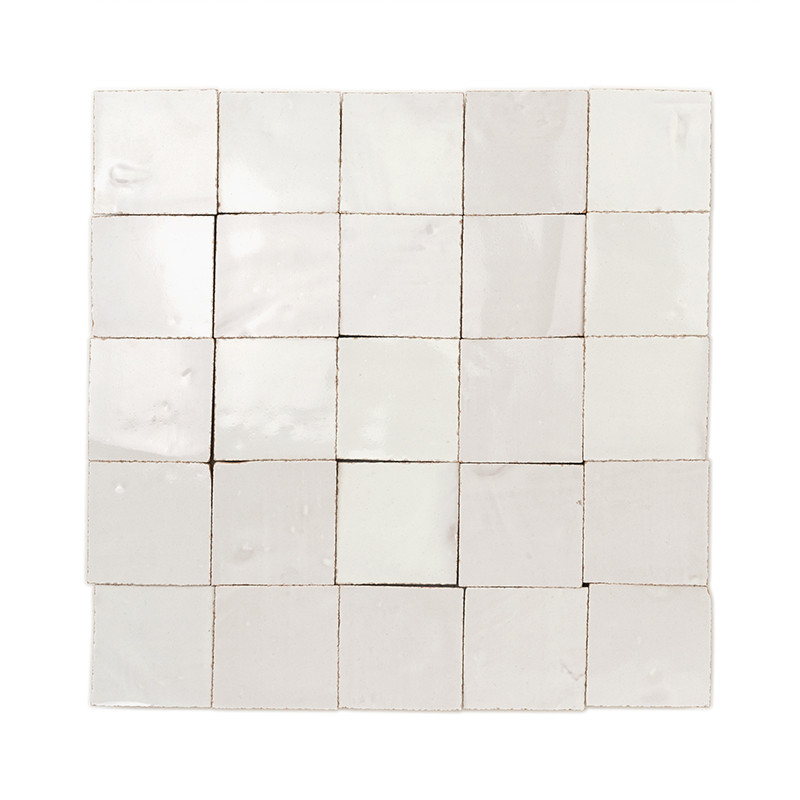 Carreaux carrés en terre cuite, présentant des surfaces brillantes et inégales, disposés en grille sur un fond blanc.