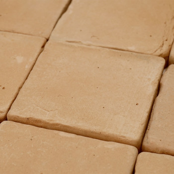 Terracottategels liggen dicht bij elkaar en vormen een uniform oppervlak met natuurlijke beige tinten en subtiele texturen in ee