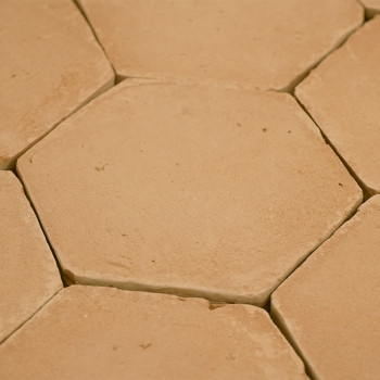 Zeshoekige terracottategels zijn dicht bij elkaar geplaatst, waardoor er kleine openingen zichtbaar zijn, waardoor een rustiek, 