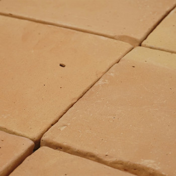 Los azulejos de terracota dispuestas en cuadrícula forman una superficie rugosa y terrosa, con ligeras variaciones de color y te
