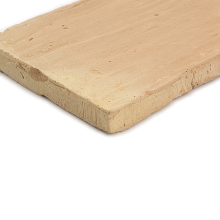 O ladrilho de terracota fica sobre uma superfície branca, apresentando uma borda áspera e natural e uma textura fosca e terrosa.