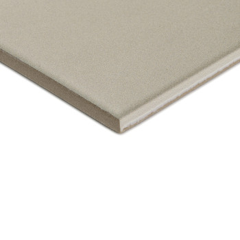 A square, gray ceramic tile with a smooth surface lies on a white background, showing its thickness with a visible edge.