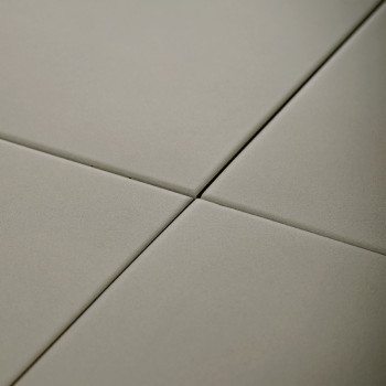 Four smooth, square tiles intersect at a central point. They form a grid pattern in a neutral, beige color.