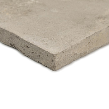 Een vierkante terracotta tegel rust op een effen, lichte achtergrond en laat een ruwe, matte textuur en onafgewerkte randen zien