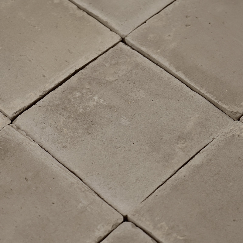 Carreaux carrés et lisses en terre cuite disposés selon un motif en grille, formant une surface aux tons neutres dans un décor i