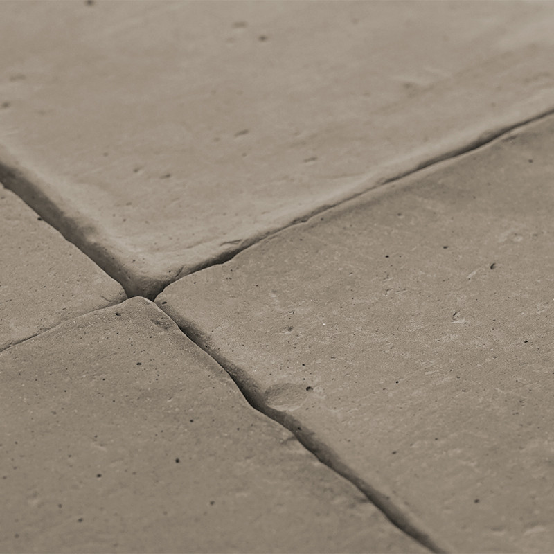 Les carreaux de terre cuite sont étroitement disposés, formant une surface texturée en forme de grille, créant un décor de sol r
