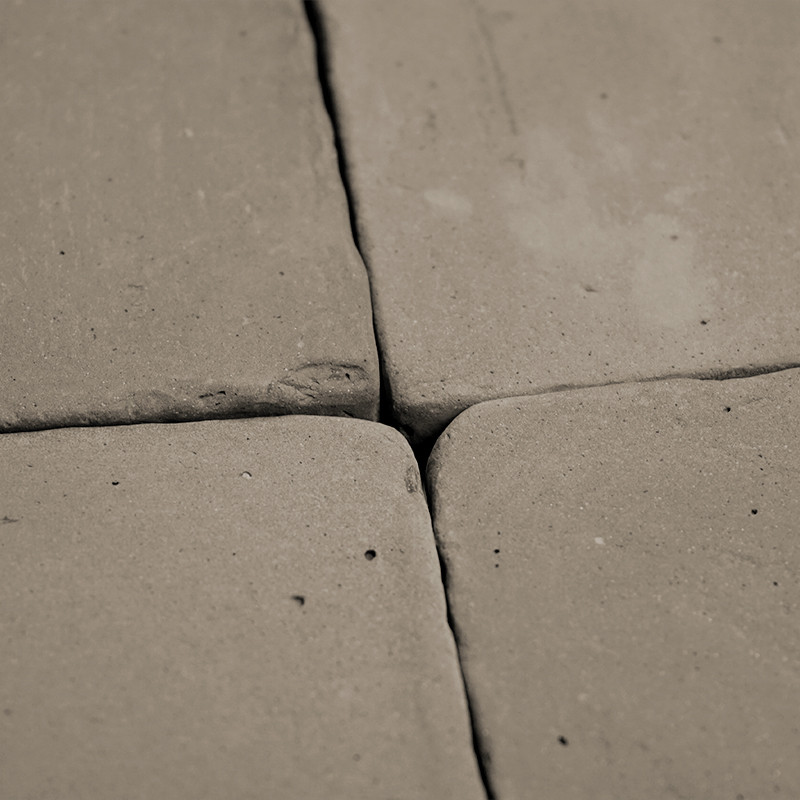 Vier terracotta tegels, dicht bij elkaar geplaatst, vormen een vierkant patroon. oppervlak vertoont een ongelijkmatige, rustieke