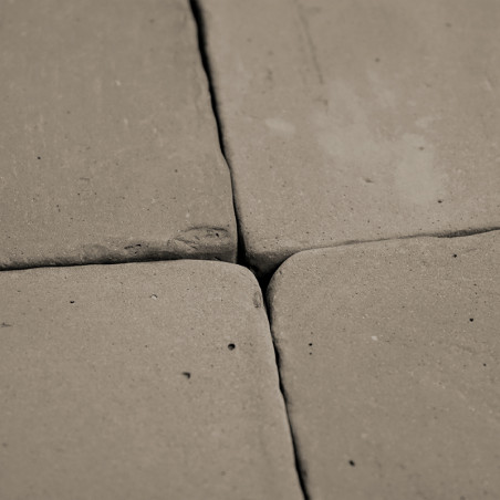 Vier terracotta tegels, dicht bij elkaar geplaatst, vormen een vierkant patroon. oppervlak vertoont een ongelijkmatige, rustieke