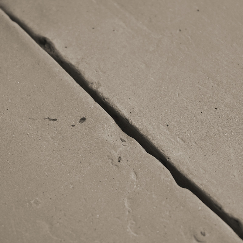 Les carreaux de terre cuite sont inégalement placés, présentant des fissures visibles et une texture légèrement rugueuse dans un