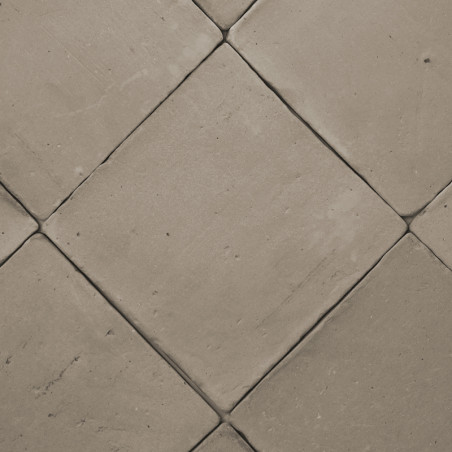 Terracottategels diagonaal gerangschikt, waardoor een ruitpatroon ontstaat op een vlak, neutraal gekleurd vloeroppervlak.