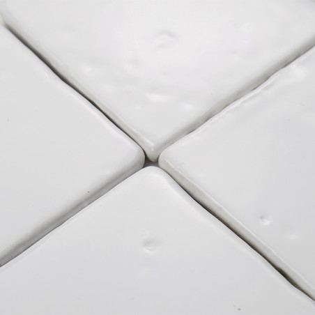 White terracotta tiles are closely laid, forming a smooth, connected surface with subtle dimples, suggesting a refined wall or f White terracotta tiles are closely laid, forming a smooth, connected surface with subtle dimples, suggesting a refined wall or f