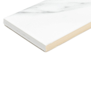 Un carreau rectangulaire blanc avec de subtils marbrures grises repose sur une surface plane. Ses bords sont légèrement relevés,