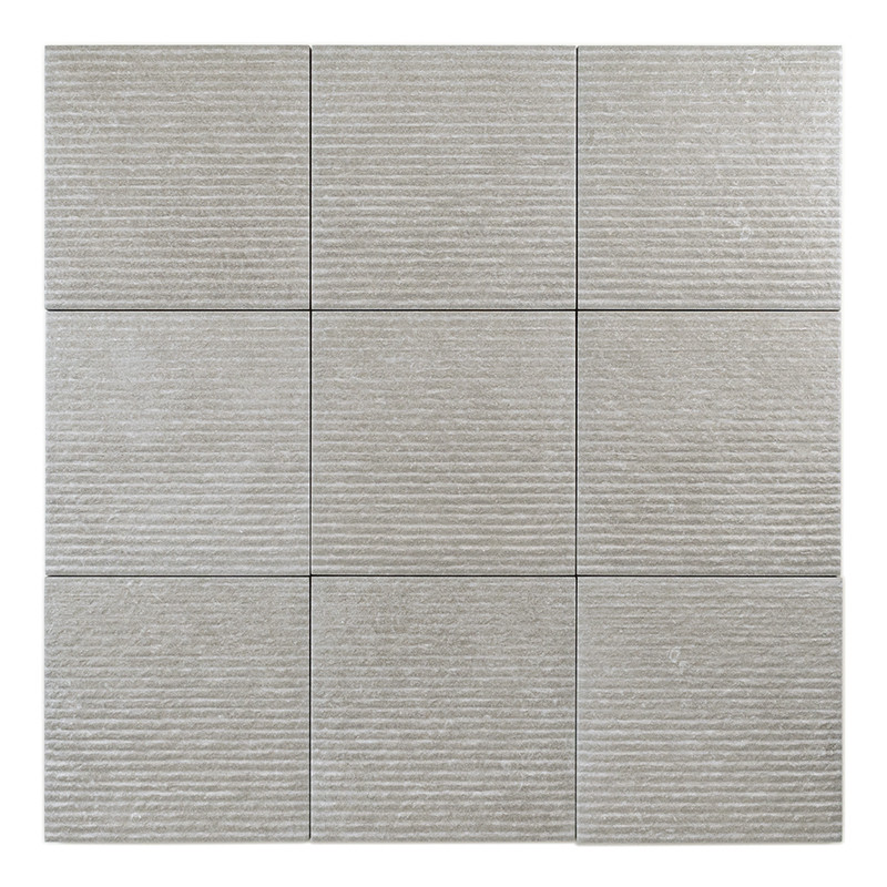 Un azulejo cuadrado de color gris claro muestra una superficie texturizada y ranuras horizontales, sobre un fondo liso y neutro.