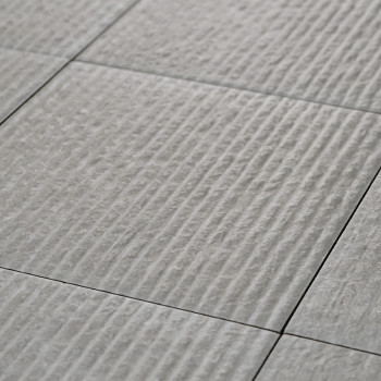 A series of light gray ceramic tiles, textured with evenly spaced horizontal ridges, form a uniformly patterned surface.