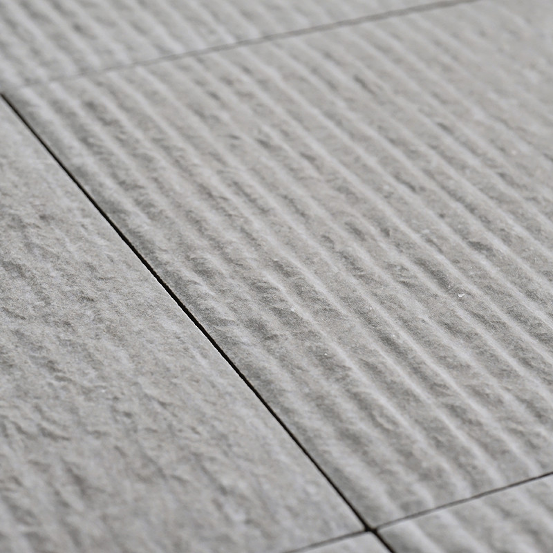 Gray ceramic tiles lie in alignment, featuring a textured surface with linear grooves, creating a subtle pattern across a flat f