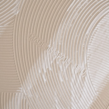 Eine beige Fliese weist geprägte konzentrische kreisförmige Rippen auf, die ein strukturiertes Muster erzeugen. In den Rillen st