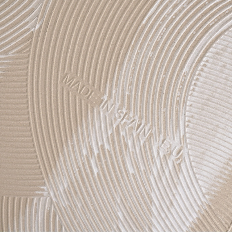 Un carreau beige présente des crêtes circulaires concentriques en relief, créant un motif texturé. Le texte indique « MADE IN SP
