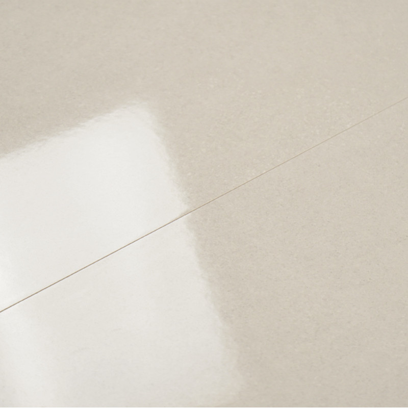Un carreau beige brillant reflète subtilement la lumière, révélant une surface lisse et uniforme. Le contexte suggère un cadre i