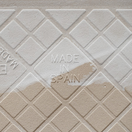 De keramische tegel in reliëf toont een geometrisch patroon met de tekst `MADE IN SPAIN` in het midden, met een mix van beige ti
