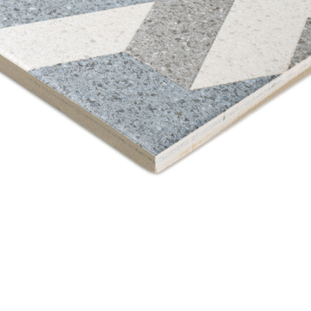 Eine Keramikfliese mit geometrischen Mustern mit grauen, weißen und blauen Abschnitten. Die abgewinkelte Kante der Fliese lässt 