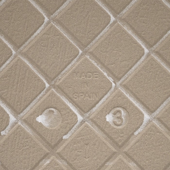 Eine beige, strukturierte Fliese mit einem erhabenen Rautenmuster zeigt in der Mitte „MADE IN SPAIN“, umgeben von subtilen Textu