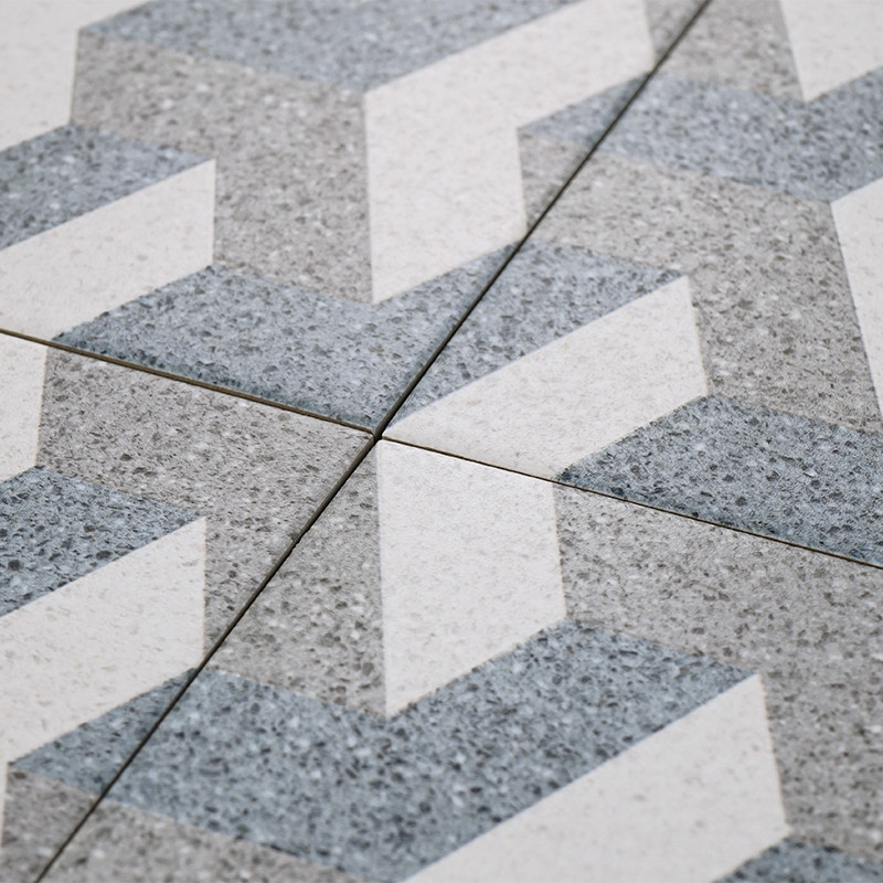 Los azulejos grises y blancos forman un patrón en zigzag, que se cruzan en las líneas de lechada, creando un diseño geométrico s